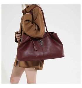 Close-up of vintage burgundy leather tote with metal cross logo and chain detail