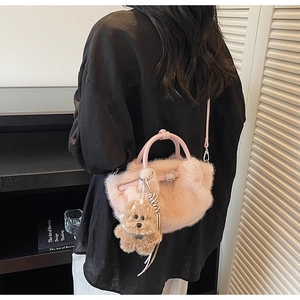 Detailed shot of pink plush faux fur bucket bag with teddy bear charm and leather handle