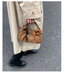 Brown suede dumpling bag with pleated design and heart pendant in a street style shot
