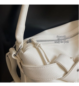 Detail of smooth silver zipper and textured white lychee pattern leather on tote bag