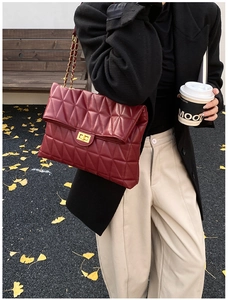 Chic quilted wine red handbag with gold chain strap in an elegant autumn street setting
