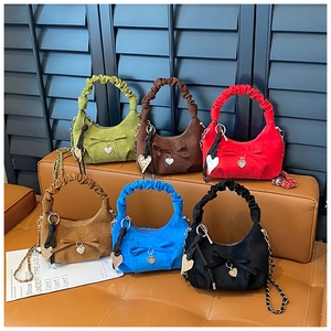 Detailed view of colorful pleated handbags with bow ties and heart pendants on a bench