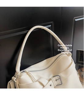 Detail of creamy white faux leather handbag showing lychee texture and metal buckle strap