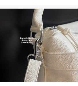 Detail of silver metal hook and white lychee pattern leather strap on motorcycle bag