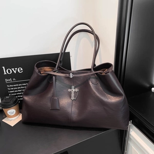 Dettaglio della borsa tote in pelle marrone scuro con croce d'argento vintage e catena