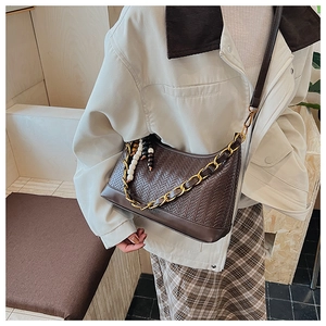 Detail der dunkelbraunen geflochtenen Tasche mit Goldkette und Perlenanhänger