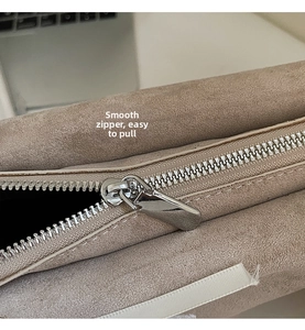 Detailaufnahme des silbernen Metallreißverschlusses an einer beigen Wildledertasche