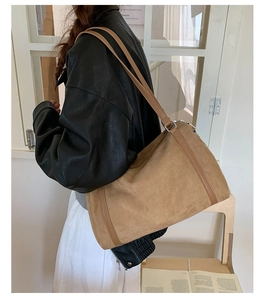 Brown faux suede shoulder bag with leather strap and silver metal links on model