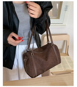 Détail du sac Boston en cuir mat marron avec fermeture éclair argentée et anses fines