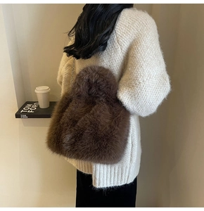 Détail du sac bandoulière en fausse fourrure marron foncé avec chaîne sur un pull en maille