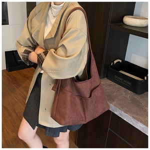 Dettaglio della borsa hobo in pelle scamosciata rosso mattone con ampia tracolla e tasca