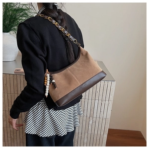 Détail du sac hobo en daim et cuir avec chaîne dorée et breloque à pompon perlé