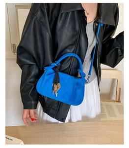Close-up of Klein blue suede bucket bag with gold heart charm and woven rope detail