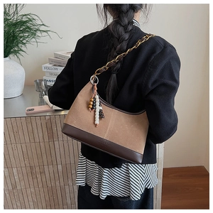 Détail du sac seau vintage en daim marron avec bandoulière chaîne et pendentif en bois