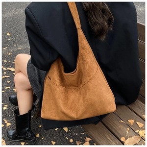 Dettaglio di borsa tote in pelle scamosciata marrone con cuciture fini autunnali