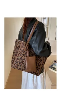 Detail of leopard print tote bag with brown leather handles and matching small pouch charm
