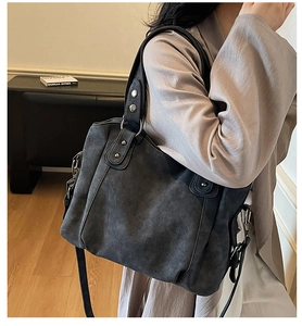 Vue détaillée d'un grand sac fourre-tout gris foncé avec anneaux et rivets en métal