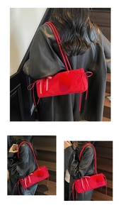Detail der roten Samt-Schultertasche mit Plüschbällen und Schleifendekor auf dunkler Treppe