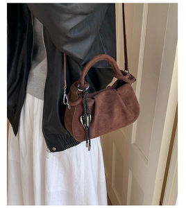 Detail of vintage dark brown suede bucket bag with pleated design and heart charm