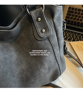 Detail of grey suede shoulder bag with silver metal ring and rivets in office setting