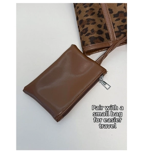 Close-up of brown faux leather zipper pouch accessory with leopard print tote bag
