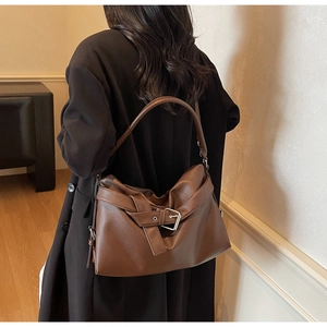 Detail of dark brown pebble leather tote bag featuring buckle accent and wide shoulder strap