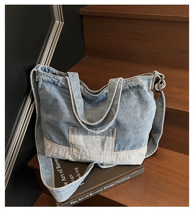 Détail du sac cabas en denim vintage avec surpiqûres sur des marches en bois sombre
