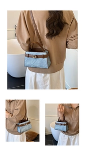 Detail of light blue crossbody bag with gold CD metal buckle and brown top handle