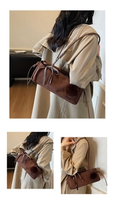 Detailaufnahme der dunkelbraunen Wildleder-Schultertasche mit Schleife und Bommel-Details
