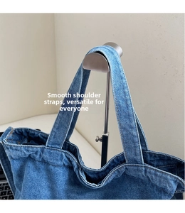 Gros plan détaillé des bandoulières du sac cabas en denim bleu et des coutures