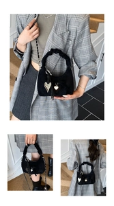 Detail of black suede crescent bag with pleated handle, metal chain and heart charms