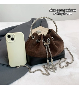 Détail du sac seau bicolore avec bandoulière chaîne et comparaison de taille avec téléphone