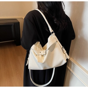 Detail view of white lychee leather texture and metal buckle on stylish tote bag
