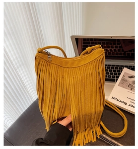 Close-up of yellow faux suede crossbody bag with vintage bohemian fringe details