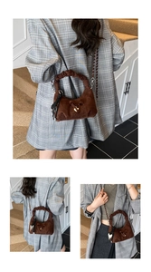 Detail view of dark brown suede crescent bag featuring knotted handle and tassel charm