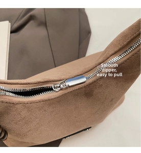 Détail macro de la fermeture éclair en métal argenté sur un sac en daim marron texturé