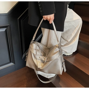 Detail of silver metallic tote bag showing wide strap and buckle on textured leather
