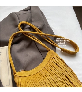 Detail of yellow suede crossbody bag featuring long fringes and smooth zipper closure