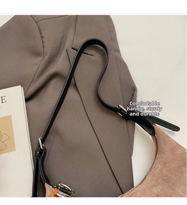 Détail de la bandoulière en cuir noir réglable et boucle argentée sur un sac en daim brun