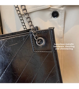 Dettaglio della borsa tote in pelle nera trapuntata con finitura lucida e catena scura