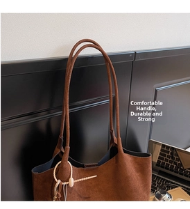 Close-up of deep brown suede tote bag featuring slim straps and minimalist artistic tag