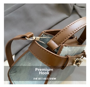 Detailed macro view of silver metal hooks and brown leather handles on a blue bucket bag