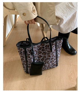 Close-up of leopard print tote bag featuring black leather handles and mini pouch charm