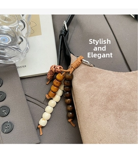 Détail du sac bandoulière en daim mocha avec breloque rétro et sangle en cuir