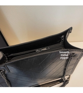 Dettaglio di una borsa in pelle nera trapuntata con cerniera in metallo scorrevole