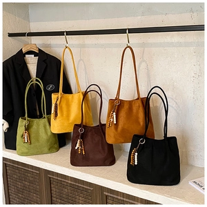 Detail view of colorful suede tote bags with distinctive beaded tassel and metal ring accents