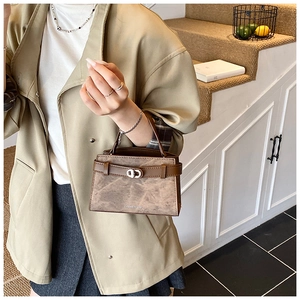 Detail of vintage brown textured handbag showing silver metal twist lock and strap