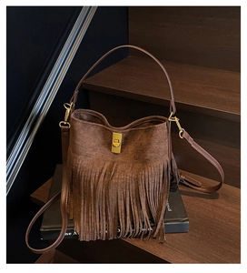 Détail du sac seau en daim marron foncé avec longues franges et fermoir doré