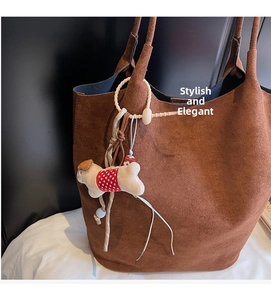 Detail of brown suede tote bag with a cute plush puppy charm and red polka dot outfit