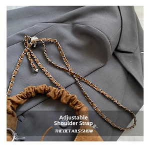 Close-up of brown suede crescent bag showing adjustable strap and chain detail